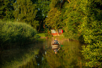 Ein Mann paddelt am Frühen Morgen in einem Kanu auf einem Fluss im Grünen
