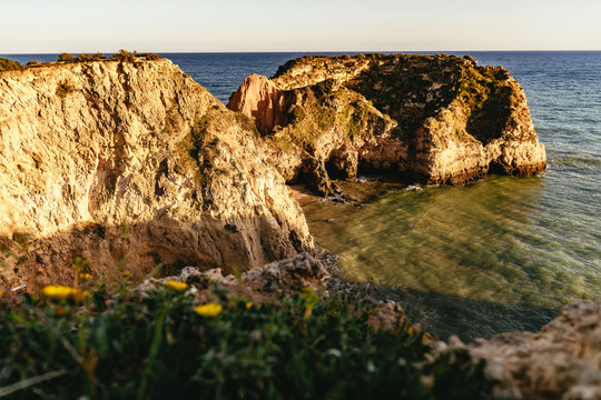 Golden limestone cliffs and sea arch at sunset
