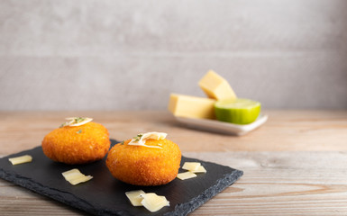 Homemade cheese croquettes on a plate with some lemon on the side.
