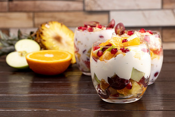 Fruit salad with yogurt, sour cream and granola in glasses. Tasty and healthy diet breakfast.