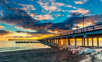 Obraz premium Colorful sunset at a famous marine pier in the Baltic resort city of Palanga, Lithuania, Europe