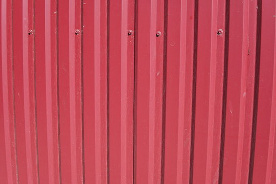 Background striped red metal profile. Texture of painted red metal surface