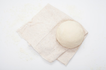 Dough on a kitchen towel, on a white background. The concept of making bread, baking recipes, to make the dough.