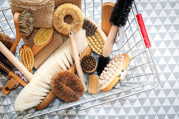 Various brooms, brushes and combs with wooden handles in the shopping basket on the tablecloth...