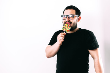 Bearded man licks a Lollipop on a light background