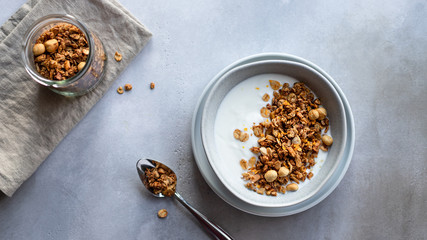 granola with nuts and natural yogurt in a bowl. Healthy and organic nutrition concept. gray concrete background. banner. copy space