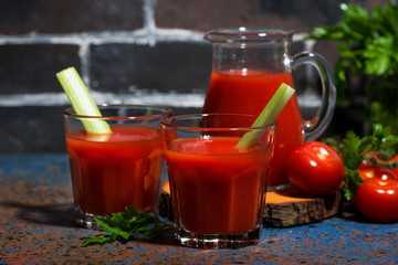 fresh tomato juice with celery in glasses on table