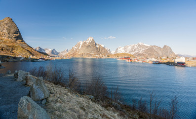 Panorama shot of Reine village in Lofoten, Norway. Snow covered mountains and nice weather with blue sky. Traveling and explorer concept.