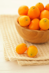 Fresh juicy natural kumquats in a wooden bowl