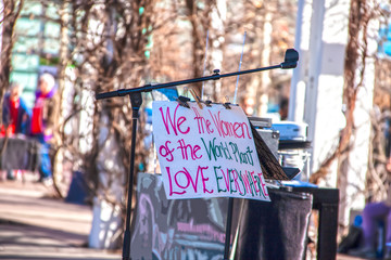 Sign clipped to microphone on stage at political rally - We the women of the world plant love everywhere