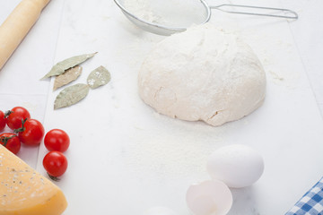 Dough, close-up, on a white background, next to tomatoes, eggs, Bay leaf and sieve. The concept of making pastries, recipes.