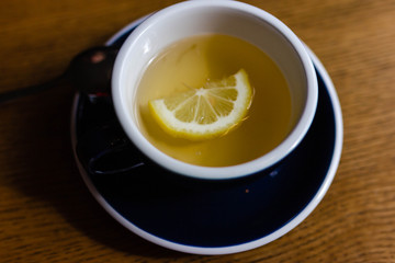 mug of green tea with a slice of lemon, a blue mug on the table.