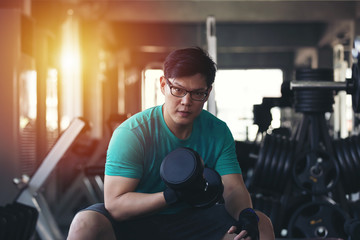 Fototapeta na wymiar Asian man lifting dumbbell weight in sport gym, healthy lifestyle concept.