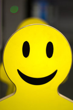 plywood tablet in the form of a silhouette of a smiley face man. Bright yellow smiley face photo taken at the airport