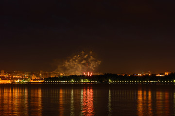 Fototapeta premium June 23, 2019: Fireworks over the evening city. View from the other side of the river. Cheboksary. Russia.