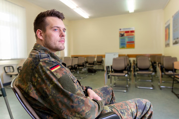 German soldier sits in a classroom . German word Bundeswehr, means german army.