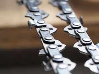 metal chainsaw chain with sharp teeth close-up with blurred background
