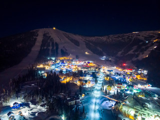 Fototapeta premium Sheregesh Kemerovo region ski resort in winter, night landscape on mountain and hotels, aerial view