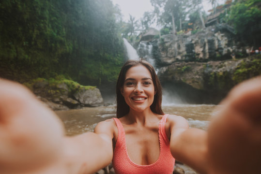 Beautiful girl having fun at the waterfalls in Bali. Concept about wanderlust traveling and wilderness culture