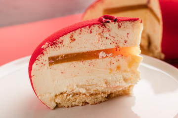 slice of red mousse cake on a plate, close up. holiday dessert