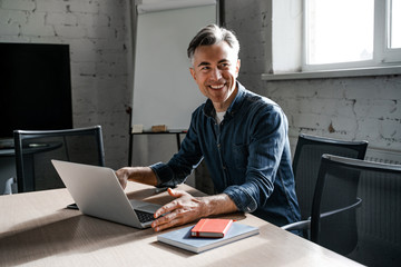 Young financial market analyst with smile working in a sunny office on a laptop. Successful...