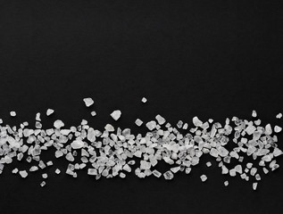 coarse sea salt scattered in a horizontal line on a black background with copy space