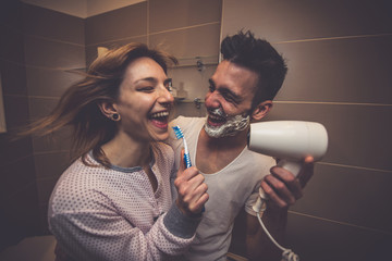 Couple morning routine. Man and woman sharing bathroom. Shaving beard and brushing teeth