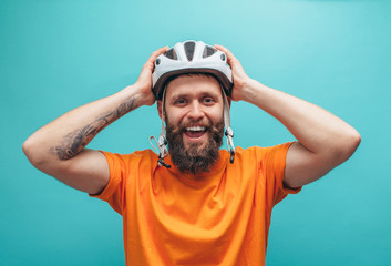 Portrait of handsome hipster guy with beard wearing blank orange t-shirt and white bike helmet,...