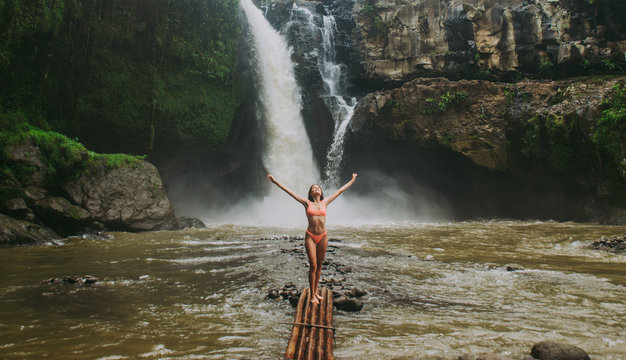 Beautiful girl having fun at the waterfalls in Bali. Concept about wanderlust traveling and wilderness culture