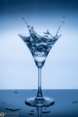  a glass of martini and splashes of liquid from an ice cube