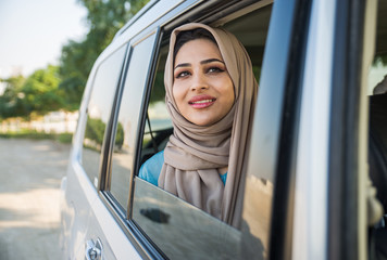 Beautiful woman in Dubai wearing abaya traditional female dress  sitting in the  car. Concept about...