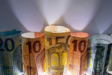 Beleuchtete und gerollte Euro-Geldscheine aus 20 euro, 50 euro, 10 euro und 5 euro Banknoten zeigen Profit, Gewinn, Ersparnisse und Dividenden im europ&auml;ischen Finanzmarkt und W&auml;hrungskursen