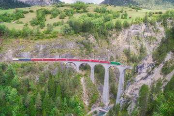 Red express train runs on famous Landwasser bridge in Filisur, the heart of Alpine mountains in Switzerland