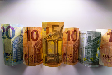 Beleuchtete und gerollte Euro-Geldscheine aus 20 euro, 50 euro, 10 euro und 5 euro Banknoten zeigen Profit, Gewinn, Ersparnisse und Dividenden im europäischen Finanzmarkt und Währungskursen