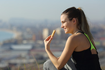 Happy runner woman eating energy bar outdoors