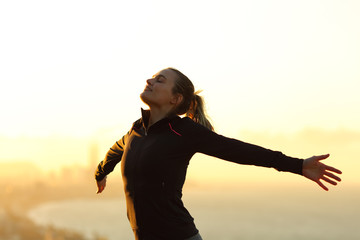 Happy runner breathing fresh air outstretching arms