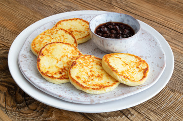 cheese pancakes with raspberry jam served on flack ceramic on wooden background