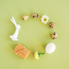 Happy easter festive circle frame. Easter layout made of various eggs, bunny figurine, flowers and craft gift on green background with copy space Creative Flat lay Top view