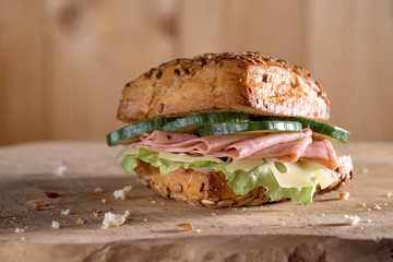 sandwich with meat, salad, cucumbers on a wooden surface