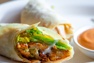 Vegetable Fillings Rolled inside an Indian Bread served on a White Plate with Mayoonaise Sauce