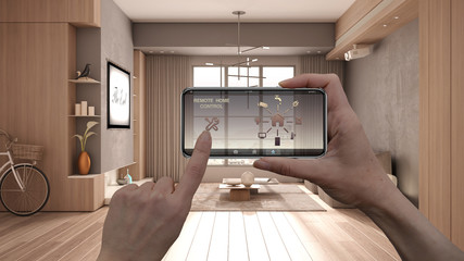 Remote home control system on a digital smart phone tablet. Device with app icons. Interior design of modern minimal living room in beige tones with armchairs in the background