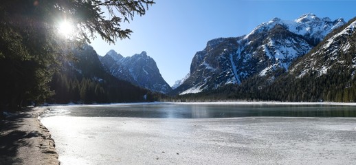 A beautiful view of the mountains and frozen lake in the morning sunlight. Lake Toblacher See (Dobbiaco) in South Tyrol, Dolomites, Italy