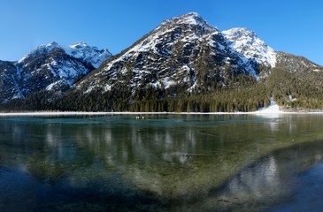 A beautiful magical view of the mountains reflected in the water in the morning sunlight. Lake Toblacher See (Dobbiaco) in South Tyrol, Dolomites, Italy
