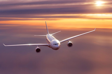 Airplane flying above morning sky at dawn.