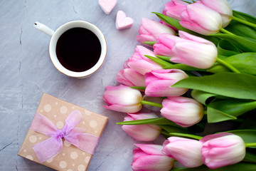 Fototapeta na wymiar A cup of coffee with sweets and tulips. A gift for mom. Mother's Day. March 8. Valentine's Day. The concept of spring. Celebratory background. Flowers with coffee and sweets. 