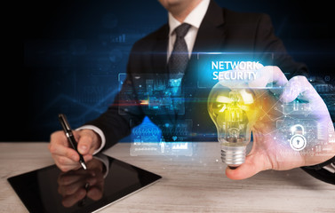 Businessman holding lightbulb with NETWORK SECURITY inscription, online security idea concept