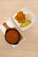Bean casserole with rice, avocado and banana fries on wood background