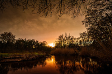 Moody sunset at a Brook at Leudal, close to Heythuysen, Northern Limburg. Sun reflected in a brook. Landscape in the Netherlands.