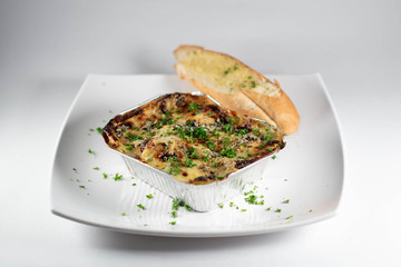 Chicken lasagna with garlic bread, baked in aluminum plate, white background