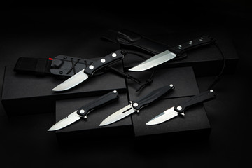 Modern hunting and penknives on a dark background. Steel arms. Folding and ordinary knives.